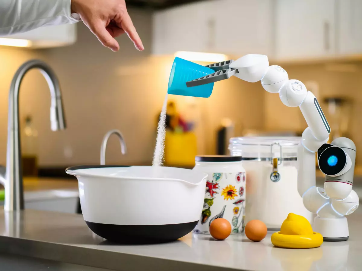 A humanoid robot arm pouring milk into a bowl, with a human hand reaching towards the robot.